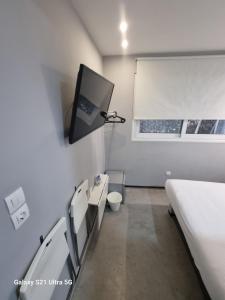 Habitación hospitalaria con cama y TV en la pared en athens.apartotel.box, en Atenas