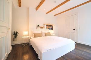 a white bedroom with a large white bed and wooden floors at Ferienwohnung Villa Wagersrott in Wagersrott +27 photos