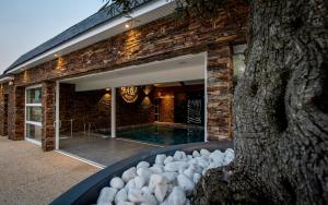 a brick house with a swimming pool and a tree at M&V Resort Camping in Langrune-sur-Mer