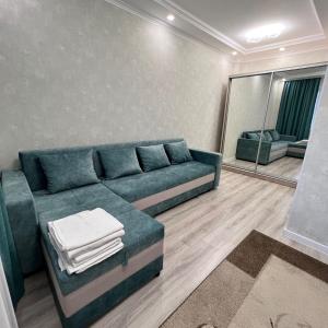 a living room with a blue couch and a mirror at Момышулы 28-433 уютно стильно in Fëdorovka