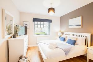 a bedroom with a white bed with blue pillows at Northern Hideaways Shore Cottage, Beadnell in Beadnell