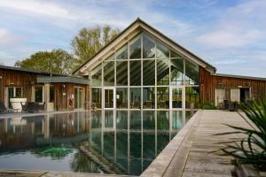 a house with a pool in front of it at Squirrels Leap Lake Views with Spa Access, Lower Mill Estate in Somerford Keynes