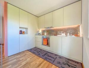 una cucina con armadi bianchi e un tappeto sul pavimento di Chez Camille & Sébastien a Bevaix