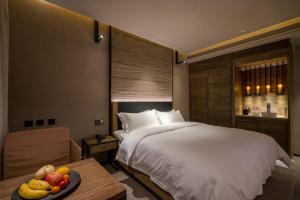 a bedroom with a bed and a table with a bowl of fruit at Jiayuguan Tuzhu Hotel in Jiayuguan