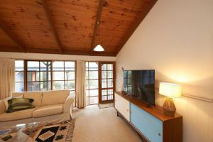 a living room with a couch and a flat screen tv at Aireys Garden Hideaway in Aireys Inlet