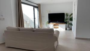 a white living room with a couch and a tv at Casa Paz en Benajarafe in Benajarafe
