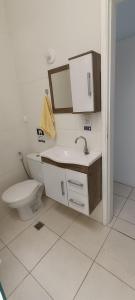a bathroom with a toilet and a sink and a mirror at Casa de praia in Praia Grande