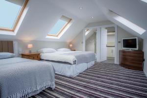 a attic bedroom with two beds and a television at Ridgeway Retreat - 1 Bedroom Cottage - Manorbier in Manorbier
