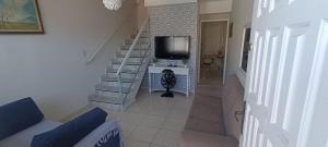 a living room with a tv and a staircase at Casa de praia in Praia Grande