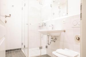 Un baño blanco con lavabo y ducha. en Jade 2, en Born 11 fotos más