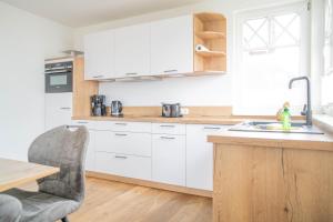 Una cocina con gabinetes blancos y una mesa y una silla. en Jade 2, en Born