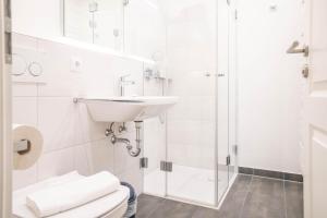 Un baño blanco con lavabo y ducha. en Jade 4, en Born 11 fotos más