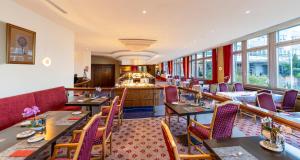 a restaurant with tables and chairs and windows at PLAZA Premium Schwerin in Schwerin