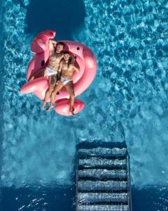 two people riding on a pink raft in a swimming pool at The Purple Hotel - Adults Only in San Antonio