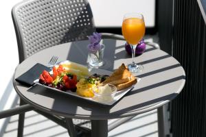 a table with a plate of food and a glass of orange juice at The Purple Hotel - Adults Only in San Antonio