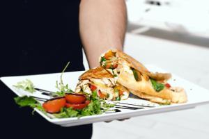 a person holding a plate with a sandwich and salad at The Purple Hotel - Adults Only in San Antonio