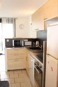 a kitchen with wooden cabinets and a black refrigerator at Bel appartement au pied des pistes 9 personnes in Saint-Lary-Soulan +1 photo