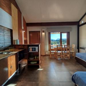 Una cocina y una sala de estar con mesa y sillas. en Flores del Limay Cabañas, en Dina Huapi