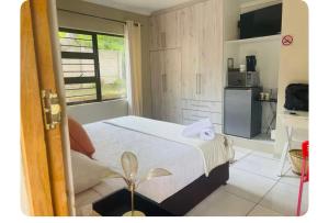 a bedroom with a white bed and a kitchen at SnaMel's in Waterfall