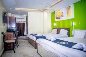 a room with two beds and a green wall at Hotel Platinum in Kolkata