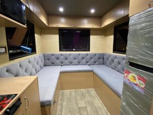迪拜Rvs Caravan Desert Setups Dubai的一个小房间,设有一张大沙发,带有厨房