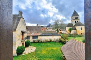 eine Gruppe von Gebäuden mit einer Kirche im Hintergrund in der Unterkunft Maison en pierre au pied de La Vézère, pour 6 in Saint-Léon-sur-Vézère