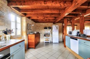 eine Küche mit Holzdecken und einem weißen Kühlschrank in der Unterkunft Maison en pierre au pied de La Vézère, pour 6 in Saint-Léon-sur-Vézère + 15 Fotos