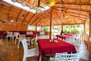 a restaurant with tables and chairs with red table cloth at YogiTree Beach Resort & Cafe - 100m from Morjim Beach in Morjim