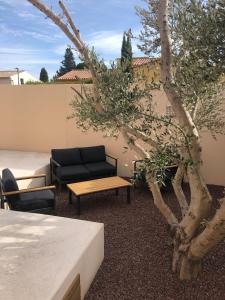 un patio con divano, tavolo e albero di La Suite a Mollégès