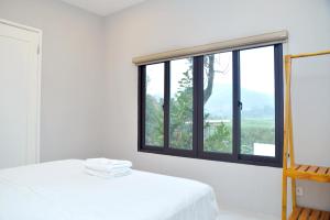 a white bedroom with a large window and a bed at Timi Little Garden in Ba Vì