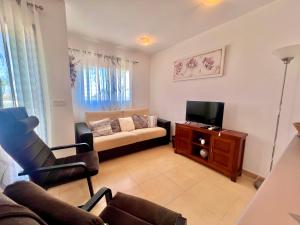 a living room with a couch and a tv at Condado de Alhama JARDIN 13 SV62 in El Romero
