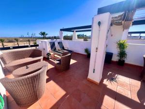 a patio with wicker chairs and tables on a balcony at Condado de Alhama JARDIN 13 SV62 in El Romero