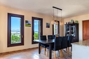 a dining room with a table and chairs and windows at Finca Estrella in Artá