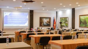 a conference room with tables and chairs and a large screen at Hotel Sileks in Ohrid