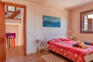 a bedroom with a bed with a red comforter at Finca Estrella in Artá