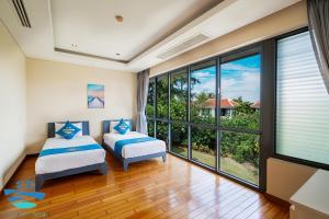 ダナンにあるAiry 3 bedroom in the Ocean Villas Da Nangのベッドが2つと大きな窓がある寝室 +109枚の写真
