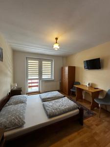 a bedroom with a bed and a desk and a television at Noclegi "Na Szczyrboku" Dom II in Korbielów