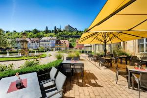 an outdoor patio with tables and chairs and umbrellas at Welcome Hotel Residenzschloss Bamberg in Bamberg