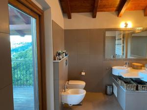 une salle de bain avec deux lavabos et un WC et une fenêtre dans l'établissement Villa Petrarca, Luxury villa with spectacular views on lake Orta, à Pella 34 autres photos