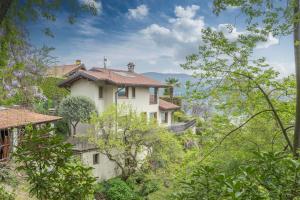une maison blanche au milieu des arbres dans l'établissement Villa Petrarca, Luxury villa with spectacular views on lake Orta, à Pella
