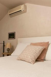 a white bed with a pillow and a air conditioner at Casa Armonia in Alassio