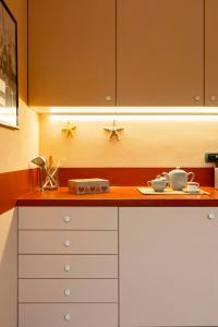 a kitchen with white cabinets and two cups on a counter at Casa Armonia in Alassio