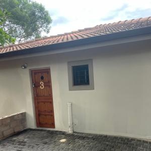 a small white house with a wooden door at SnaMel's in Waterfall