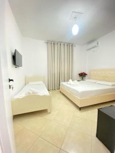 two beds in a room with a tv at Enel Villa in Sarandë