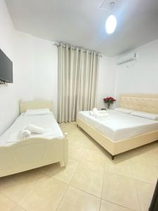 two beds in a white room with a tv at Enel Villa in Sarandë