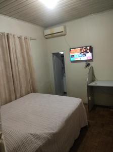a bedroom with a bed and a tv on the wall at Posada Dale Dale in São Gabriel