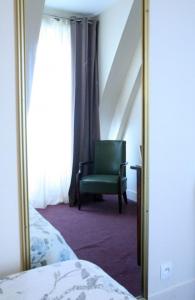 a mirror next to a bedroom with a green chair at Grand Hôtel De L'Europe in Paris