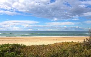 una playa con el océano en un día nublado en Bougainvillea, en Sawtell