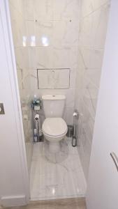 a bathroom with a toilet in a white tiled room at Suite Prestige Paris-La Défense Balcon-Terrasse in Courbevoie +40 photos