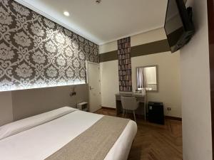 Un dormitorio con una cama, un escritorio y un televisor. en Hostal Atocha Almudena Martín, en Madrid